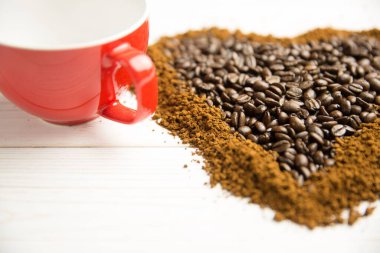 Düz tasarım kahve çekirdekli kahve masasında kırmızı seramik kahve fincanı gösteriyor. Sanatsal, samimi, rustik, aromatik, sıcak, minimalizm, konukseverlik