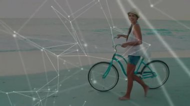 Soldan gelen kadın turkuaz bisikleti kıyıda itiyor, teknoloji için ağ örtüsü gösteriyor. Sahil, sahil, boş zaman, açık hava, minimalist, dinginlik, dijital