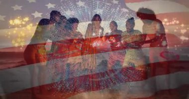 Kumsalda kıvılcımları yakmaya yardım eden arkadaşlar, patlayan dijital havai fişekler ve yükselen bayrak. Kutlama, birlik, alacakaranlık, coşku, dostluk, sıcaklık, rahatlık.