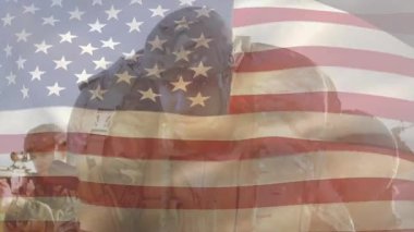 Asker, yoldaşı kucaklıyor miğferi ayarlıyor ve askeri birliği gösteren bayrak ile selamlıyor. Askeri, yoldaşlık, vatanseverlik, disiplin, cesaret, dayanışma, dayanıklılık