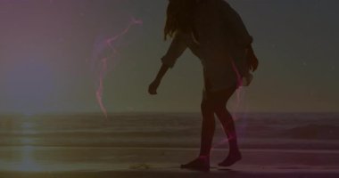 Plajda dolaşan bir kadın mor yüzük teknolojisini etkinleştirirken deniz kabuğunu seçiyor sonra da köpek için atıyor. İzole, sakin, fütürist, yansıtıcı, sükunet, macera, minimalizm