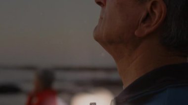 Yumuşak solmuş haç örtüsü, yaşlı adam denize bakıyor, yaşlı kadın sağlık kitabını düşünüyor. Maneviyat, tefekkür, dinginlik, saygı, farkındalık, bağlılık, içgözlem.