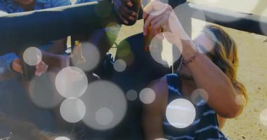 Arkadaşların bira şişesini uzatıp tost yapıyor ve pazarlama için kumlu cipin altında güneşi kutluyorlar. Açık hava, dostluk, rahatlama, kutlama, yaz, eğlence, yaşam tarzı.