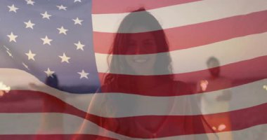 Üç arkadaş alacakaranlıkta Amerikan bayrağı pazarlama için ışık ve kıvılcımlar sallıyor. Kutlama, dostluk, açık hava, şenlik, alacakaranlık, neşe, birlik