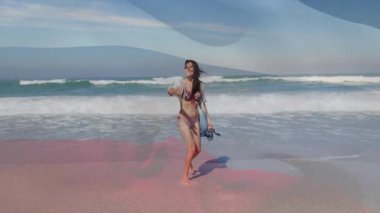 Seyahat meraklısı ıslak kıyı şeridine adım atıyor ve okyanus esintisini kucaklarken şalı kaldırıyor. Sahil, meltem, boş zaman, açık hava, doğal huzur, moda.