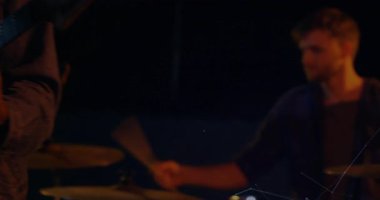 Grup, bateri çalarak ve gitarı tıngırdatarak müzik programını başlatıyor. Müzisyenler, performans, sahne, enerji, işbirliği, ses, ritim