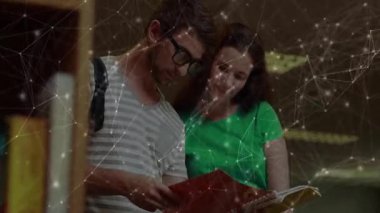 Eğitim kütüphanesindeki ahşap rafı karıştıran iki sınıf arkadaşı kırmızı klasörü çekip sayfaları onaylıyor. İşbirliği, öğrenim, bilgi, arkadaşlık, okur yazarlık, organizasyon, öğrenim