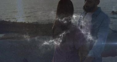 Sahilde kadını kaldıran adam gün batımında teknoloji gösterisiyle etrafını saran kıvılcım saçan nebula çifti. Romantik, samimi, göksel, çevresel, fantastik, dijital, ruhani