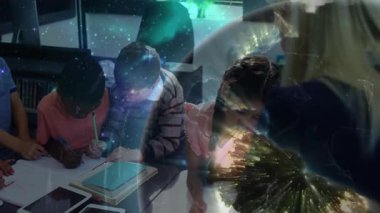 Öğretmen sınıfta yazan öğrencinin üzerine eğiliyor ve öğrenmeyi yönlendirirken çalışma kağıdını yerleştiriyor. Eğitim, sınıf, öğrenim, öğrenci, öğretim, okul, okur yazarlık