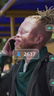 Akıllı telefon kullanan Afrikalı Amerikalı albino adama karşı sosyal medya simgelerinin animasyonu. Sosyal medya ağı ve iş teknolojisi kavramı