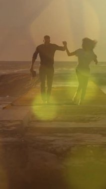 Afrika kökenli Amerikalı çiftlerin üzerinde sarı ışık lekeleri var. Deniz kenarındaki kayalarda el ele yürüyorlar. Aşk ve ilişki kavramı