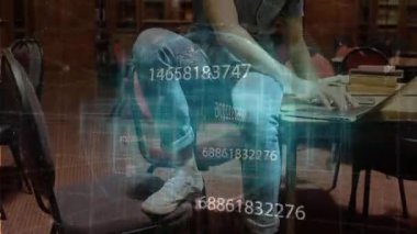 Öğrenci kırmızı sandalyeye oturmuş dizüstü bilgisayarda yazı yazıyor veri akışını analiz ediyor akıllı telefonları dinliyor ve gülümsüyor. Zeka, yenilik, üretkenlik, modern, konsantrasyon, teknoloji, çalışma alanı