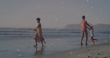 Seyahat eden aile kumsala varır, ebeveynler çocuklarla yürürken baba da bağ kurmak için kızını sallar. Tatil, boş zaman, açık hava, bağlanma, mutluluk, neşe, neşe