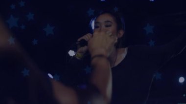 Gözleri kapamak ve mikrofonu kavramak, hayranlar yıldızların altına uzanırken şarkıcının müzik başlatması. Performans, konser, sahne, aydınlanma, coşku, seyirci, müzik