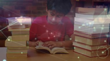 Çocuk masa üzerinde kitap açıyor ve yüzen dijital grafikleri aktifleştirirken aynı zamanda öğrenmeyi geliştiriyor. Gençlik, eğitim, kütüphane, teknoloji, konsantrasyon, öğrenim