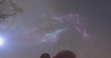 Sahile yaklaşan bir çift astronomi eğitimi için tepemizde sürüklenen nebulaya hayran. Yıldızlara bakan, romantik, kozmos, siluet, sükunet, gece manzarası, göksel