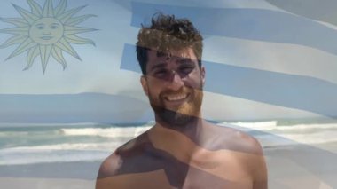 Tişörtsüz bir adam kayıyor, kumsalda gülümsüyor, hayalet bayrak ile birlikte seyahat reklamları için rüzgarla sürükleniyor. Sahil, deniz manzarası, portre, boş zaman, doğal, enerjik, iyimserlik.