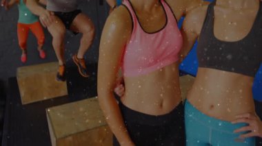 Öndeki kadınlar poz veriyor ve kamera genişletme fitness sınıfı olarak diğerlerini motive ediyor. Grup fitness, egzersiz, atletizm, motivasyon, güç, yoldaşlık, eğitim