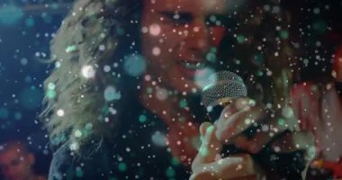 Kamera, erkek şarkıcının mikrofonu kavradığını ve daha sessiz bir şekilde şarkı söylediğini gösteriyor. Performans, konser, müzik, vokal, sahne, ışıklandırma, eğlence