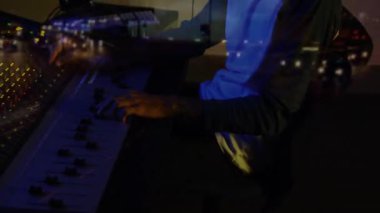 Ses mühendisi sürgülü faders, stüdyoda kulaklık takmak, şehir ışıklarını grup karışımıyla birleştirmek. Stüdyo, teçhizat, gece hayatı, ses, şehir, ortam, teknoloji