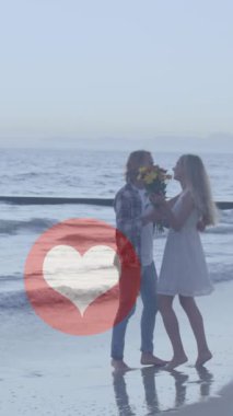 Sahilde öpüşen beyaz bir çifte karşı birden fazla kırmızı kalp ikonu. Sosyal medya ağı ve teknoloji kavramı