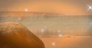 Kıvılcımlar görünür ve sürüklenirken dinamik arka plan efektleri için plajda titreşir. Deniz manzarası, sükunet, doğal, dingin, parıltılı, alacakaranlık, manzara