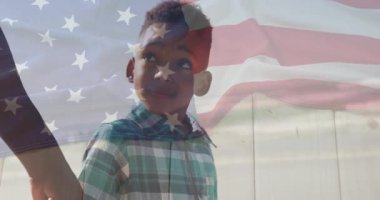 Görüş alanına adım atan baba, çit boyunca Amerikan bayrağı altında oğluna rehberlik eden, gülümseyen çocuk. Aile, vatanseverlik, akıl hocalığı, bağlantı, açık hava, miras, masumiyet.