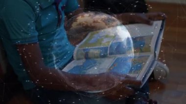 Erkek çocuk atlas sayfalarını çeviriyor ve coğrafya eğitimini keşfederken dönen dünyayı başlatıyor. Çocuk, eğitim, öğrenme, hayal gücü, teknoloji, keşif, merak