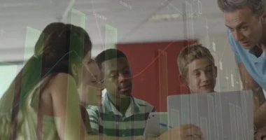 Öğretmenler dizüstü bilgisayara eğilip işaret ediyor, öğrenciler sezgi için finansal grafiklere dikkat çekiyorlar. Eğitim, işbirliği, teknoloji, veri, öğrenme, yenilik, sınıf