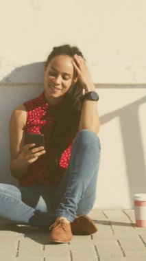 Sokakta oturan akıllı telefon kullanan Afrikalı Amerikalı kadınlara karşı birden fazla kalp ikonu var. Sosyal medya ağı ve teknoloji kavramı