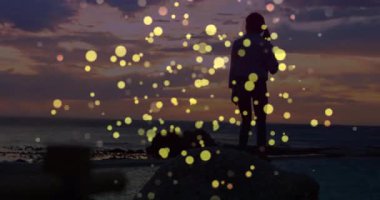 Gün batımında kayalık kayalıklarda duran kadın altın parçacıklar sürüklenirken, gün batımını karşılayan kollar kaldırıyor. Meditasyon, sükunet, siluet, doğa, farkındalık, sağlık, sükunet