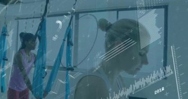 Yoga öğrencisi havadaki hamak döngüsüne giriyor ve eğitmen askıya alınmış kalasları ayarlıyor. Hava yogası, süspansiyon, esneklik, fitness, eğitim, sağlık, stüdyo