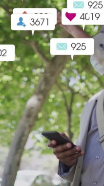 Akıllı telefon kullanarak sosyal medya simgelerinin Afro-Amerikan maskeli adam üzerinden canlandırılması. Sosyal medya ağı ve iş teknolojisi kavramı.