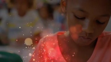 Kameralı zumlayan öğrenci ödevini yaparken okulda sınıf arkadaşlarının üzerinde kırmızı parıltılar süzülüyor. Eğitim, öğrenim, odaklanma, sınıf, yaratıcı, ilham, çeşitlilik