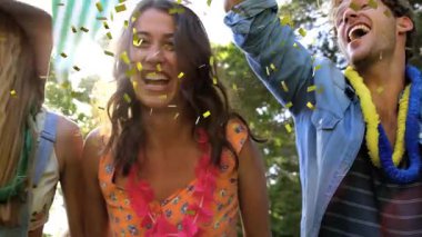 Arkadaşlar kollarını kaldırıyor ve konfeti yağmuru başlatıyorlar. Promosyon için çiçek kolları ve pankartlarla. Kutlama, neşe, birlik, açık hava, coşku, mutluluk, parti