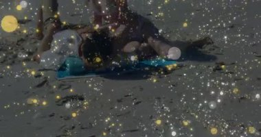 Çizgili havluyla güneşlenen çift güneşe maruz kaldığını hissediyor ve cilt bakımı için losyon sürüyor. Romantizm, boş zaman, açık hava, rahatlama, yaz zamanı, samimiyet, sağIık.