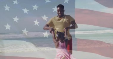 Babası, kızı kıyı şeridinde bayrak örtüsüyle onu güneşli plajda döndürüyor. Aile, eğlence, açık hava, portre, eğlence, neşe, neşe