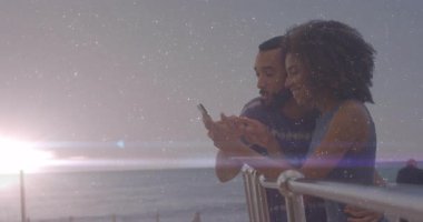 Günbatımında korkuluklara dayanan akıllı telefonu alan ve teknolojiyi keşfedip anı paylaşan çift. Romantizm, mahremiyet, doğal, açık hava, alacakaranlık, boş zaman, bağlantı