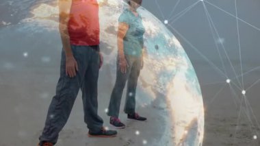 Çift, plajda kol kaldırarak vücut geliştirme egzersizi yapıyor. Dönen küre ölçülerini gösteriyor. Fitness, wellness, outdoor, digital, technology, sedentary, health