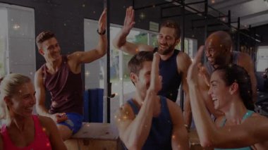 Öndeki kadınlar el kaldırıyor ve kontryo kutularının etrafındaki fitness meraklıları arasında beşlik çakıyor. Fitness, dostluk, takım çalışması, motivasyon, aktif, işbirliği, kahvaltı