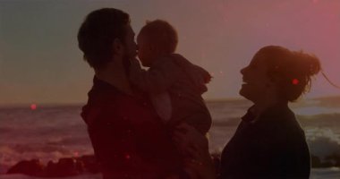 Anne ve baba gün batımında bebeğe dokunuyor, anne ve bebek merceklerle ebeveynlik yapıyor. Aileler, ebeveynlik, bağlılık, açık hava, dinginlik, şefkat, sıcak