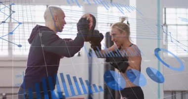 Antrenör eldiveni değiştiriyor, boksöre rehberlik ediyor spor salonunun verilerine yumruk atıyor ve ayak hareketlerini test ediyor. Eğitim, spor, atletizm, dayanıklılık, rekabet, dinamik, performans