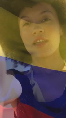 Kolombiya bayrağının sahilde kameradan selfie videosu çeken bir kadının üzerinde dalgalanması. Dijital bileşim, çoklu pozlama, tatil, tatil, hükümet, vatanseverlik ve teknoloji.