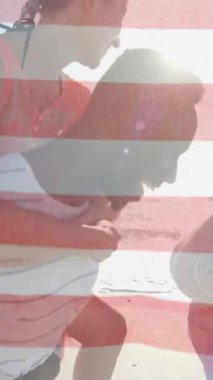 Amerika bayrağının yaz aylarında kumsalda kadınları sırtında taşıyan mutlu erkekler üzerindeki animasyonu. Amerikan vatanseverliği, çeşitlilik ve tatil konsepti dijital olarak oluşturulmuş video.
