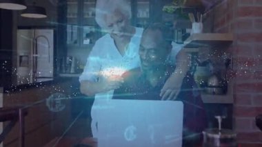 Üst düzey çift mutfaktaki dizüstü bilgisayarda jestlerini paylaşıyorlar ve avro büyümesini gösteren bir finansman sembolü oluşturuyorlar. Bağlantı, samimiyet, sıcaklık, teknoloji, dijital, veri, yenilik