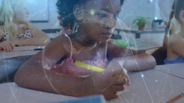 Öğrenci masaya uzanıyor ve sınıf çizimine devam eden tutucudan renkli kalemi alıyor. Öğrenim, eğitim, yaratıcılık, sınıf, takım çalışması, gençlik, ilham