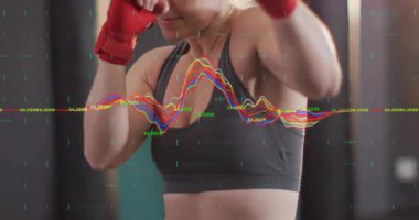 Kırmızı sarılı yumruklar sallayan bir kadın stüdyoda gölge boksu başlatırken dalga boyu yumruklarla senkronize oluyor. Spor, dövüş sanatları, eğitim, güç, çeviklik, spor, hareket