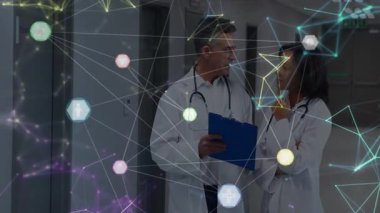 İki doktor koridorda verileri incelerken şeffaf şebeke tıkırtıları zayıflıyor. Tıbbi, işbirliği, dijital, yenilik, sağlık, profesyonellik, takım çalışması