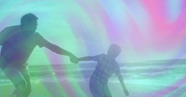 Kıta şeridinde kıyı şeridinde çocuğun elini dalgalarla tutuyor ve sağlık teması için neşeli bir koşu rehberliği yapıyor. Nesil, bağ, açık hava, boş zaman, macera, aktivite, bağlantı