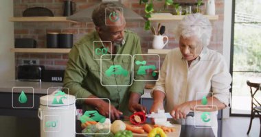 Kadın mutfakta soğan düzenlerken erkek biber topluyor ve kesiyor. Sürdürülebilirlik simgeleri gösteriyor. Aşçılık, işbirliği, çevre dostu, yerli, yaşam tarzı, aşçılık, tazelik